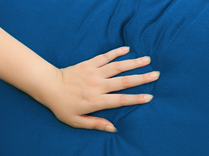Close-up product demonstration showing a hand pressing on a blue textured surface or fabric