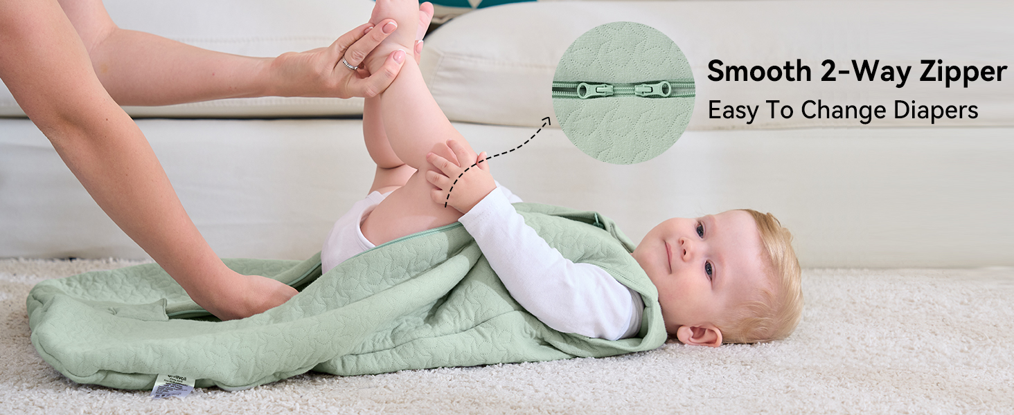 Grüner Babyschlafsack mit Händen, die über einen glatten 2-Wege-Reißverschluss verfügen. Der Text weist darauf hin, dass es einfach ist, Windeln zu wechseln