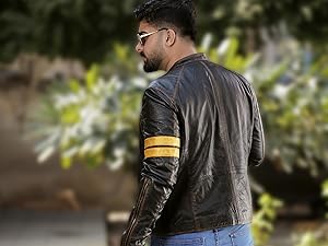 Braune Lederjacke mit gelbem Armstreifen, getragen von Personen mit Bart und Sonnenbrille. Die Jacke verfügt über strukturierte Einsätze und sichtbare Nähte
