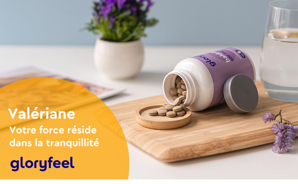 Récipient à suppléments violet et blanc avec des pilules exposées sur une surface en bois, à côté d'une plante en pot et d'un verre d'eau