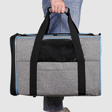 Große graue Reisetasche mit schwarzen Griffen und Riemen, getragen von einer Person, die Jeans trägt. Geräumiges rechteckiges Design für Reisen oder den Einsatz im Fitnessstudio.