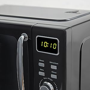 Black microwave oven control panel showing green digital clock display reading 10:10, with chrome handle and multiple control buttons visible.