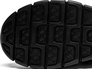 Close-up of a black rubber shoe sole with a geometric tread pattern featuring rectangular shapes and grooves for traction.