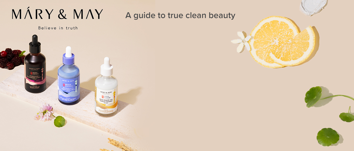 Three skincare product bottles from Mary & May brand, displayed with fruit slices and flowers on a beige surface. Text reads 'A guide to true clean beauty'.