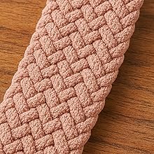 Close-up of dusty pink braided elastic band with intricate basket-weave pattern texture on wooden surface.
