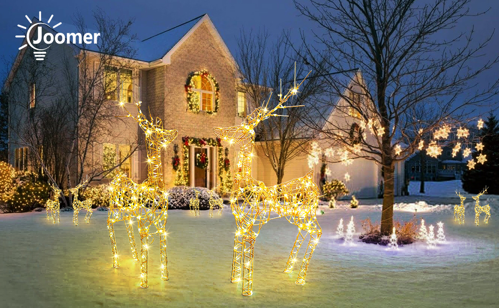 Two-story brick house with illuminated Christmas decorations, including light-up reindeer and trees on a snow-covered lawn.