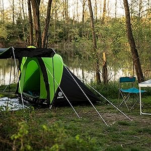 montada junto a un lago con mesa y sillas plegables, rodeada de árboles en un entorno natural.