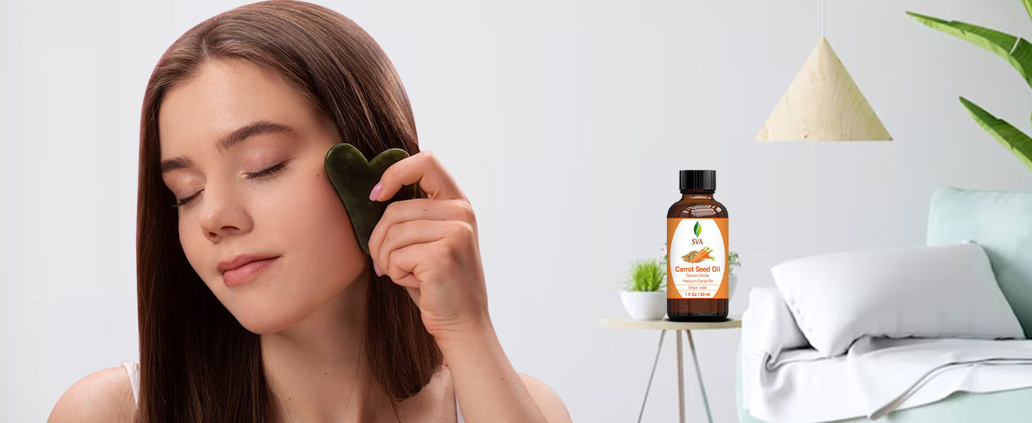 A lady massaging her face using carrot seed carrier oil from amber glass bottle for skincare