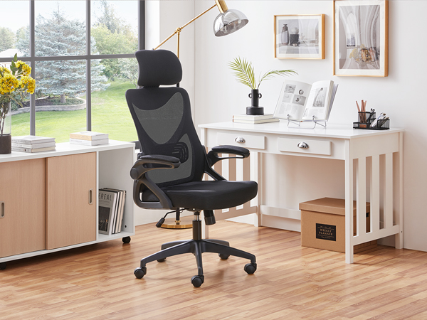 Ergonomic office chair with black mesh back, headrest, and adjustable armrests. Positioned at a white desk in a bright home office setting.