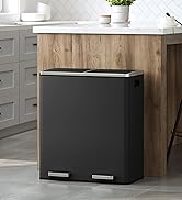 Large black rectangular trash can with dual compartments and metal pedals, situated in a kitchen setting next to wooden cabinetry.