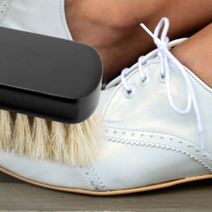 lady polishing her white shoes with a white horse hair shoes brush