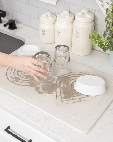 Stone dish drying mat absorbing water, keeping the kitchen countertop pristine and dry.