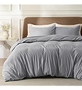 Grey bedding set displayed on bed with matching pillowcases against neutral wall background. Shows textured duvet cover in soft, muted tones.