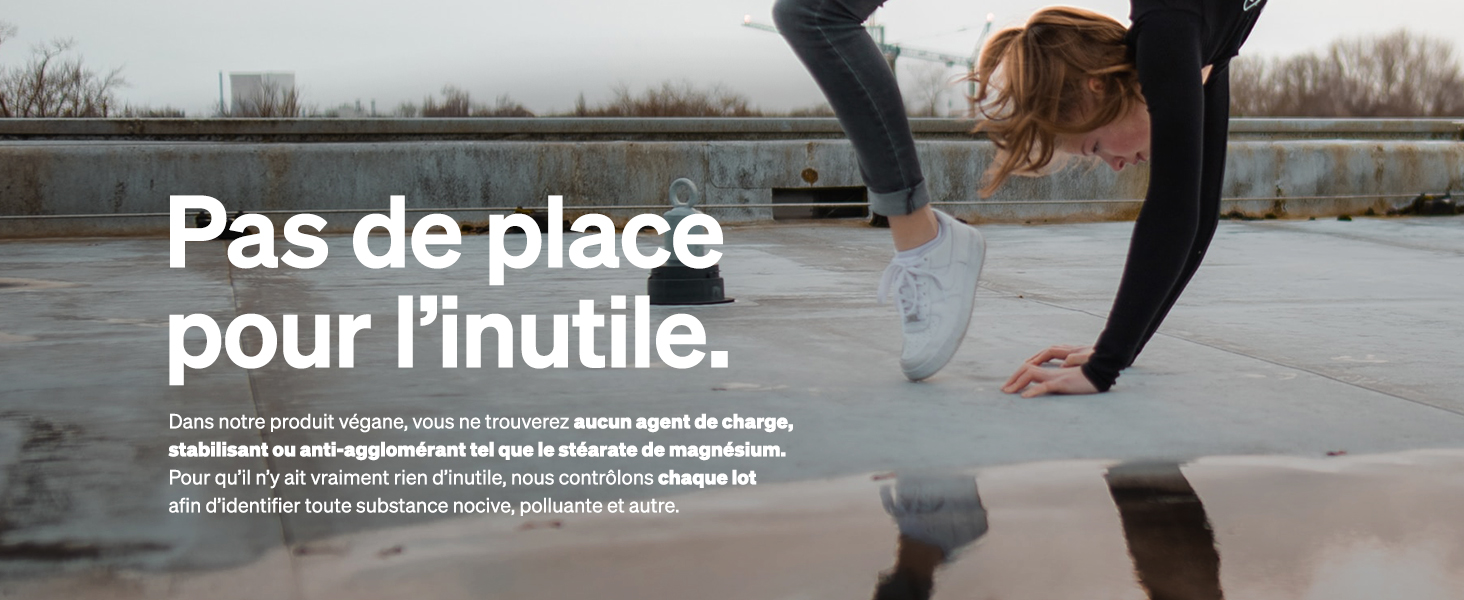 Personne s'étirant sur une surface en béton, portant des baskets blanches et des leggings foncés. L'horizon urbain est visible en arrière-plan.