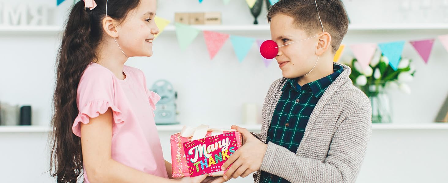 A girl celebrating birthday with her friend is holding a cake and thank you notes with envelopes.