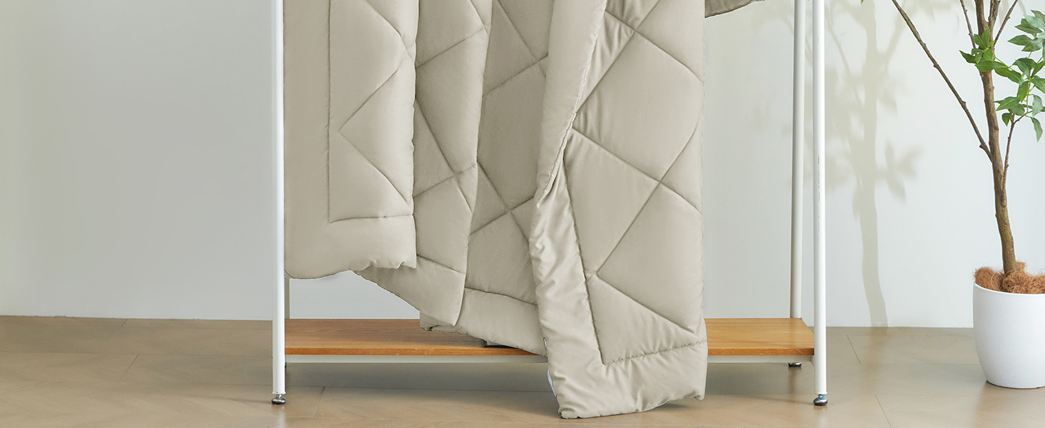 Quilted beige comforter or duvet draped over a wooden rack or stand. The bedding has a diamond-stitched pattern and appears plush and cozy.