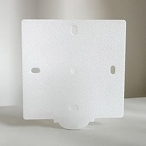 Assiette carrée texturée blanche avec de multiples découpes et une languette saillante en bas. La surface a un aspect granuleux légèrement rugueux