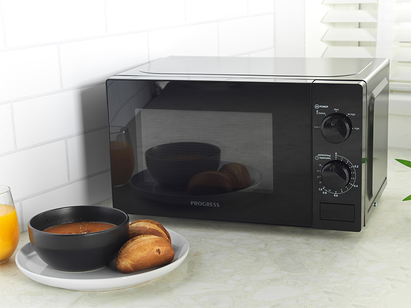 microwave with two turn dials with a bowl of soup and bread, the microwave is on a kitchen counter
