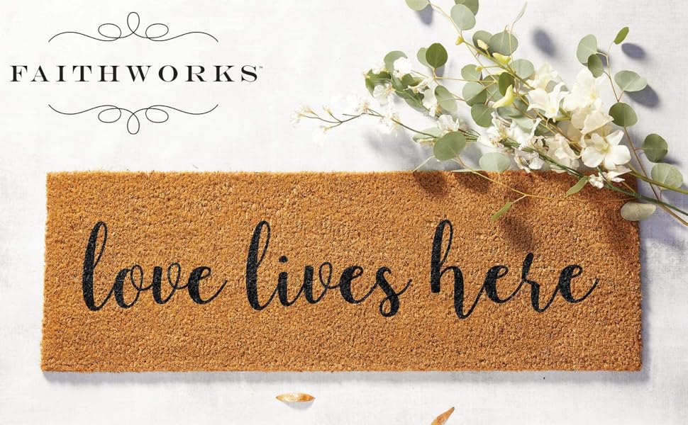 brown coir doormat with cursive lettering reading love lives here beside a white flower bunch
