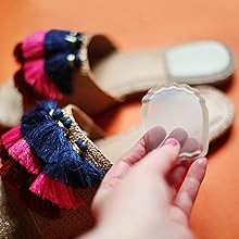 Women holding a gel heel cushion into a tasseled flat sandal.