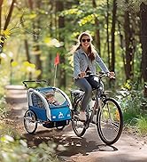Bicycle with attached blue child trailer on forest path. Bike features upright riding position and front basket. Trailer has safety flag and transparent cover for child passenger visibility.