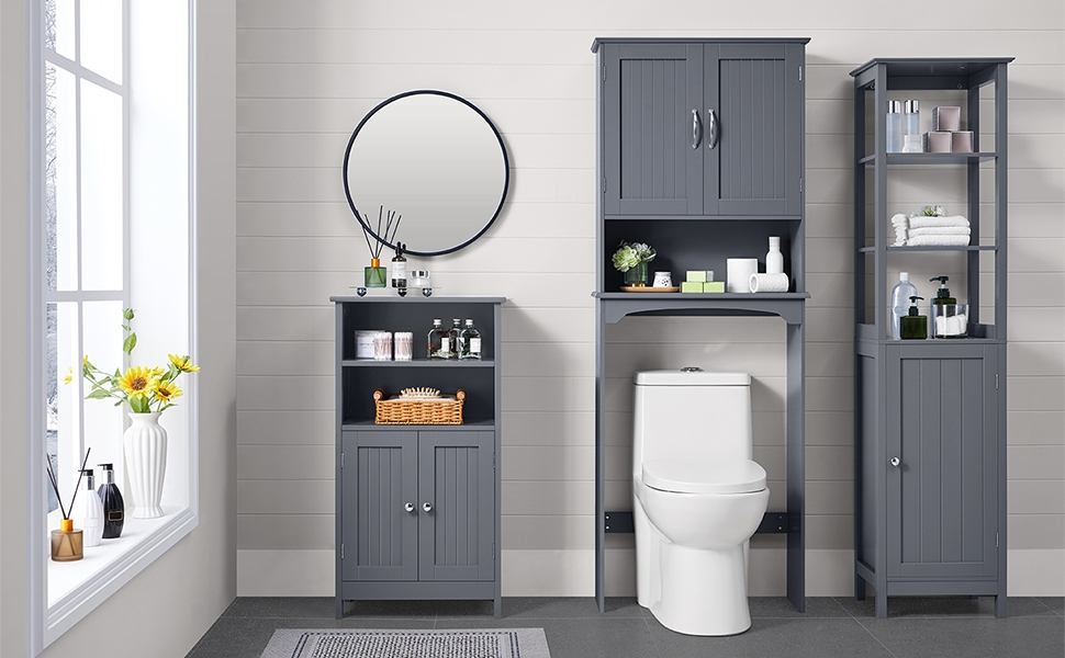 Gray bathroom storage set including over-toilet cabinet, tall cabinet, and floor cabinet. Round mirror and decorative items on windowsill complete the modern bathroom scene.