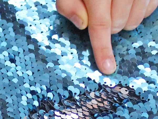 Close up of sequins being flipped by kid. 