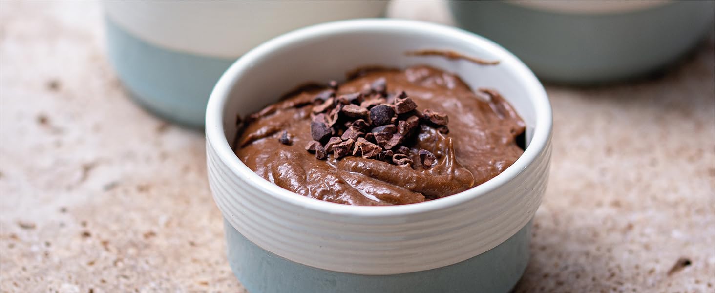 Bowl of smooth chocolate mousse or pudding topped with chocolate shavings, served in a white ceramic dish.
