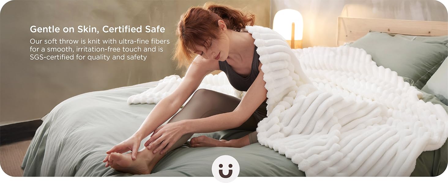 Person sitting on a bed with white textured comforter, reaching down to touch their toes in a stretching position.