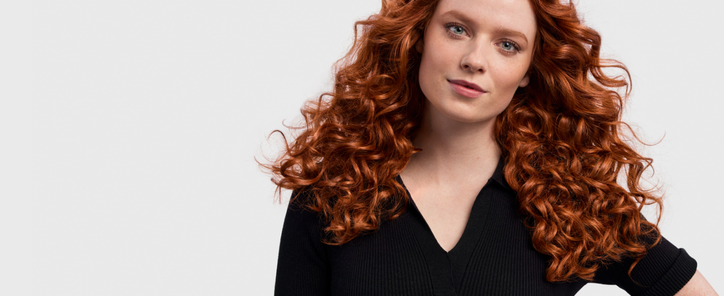 Model with red wavy hair styled into 80’s curls