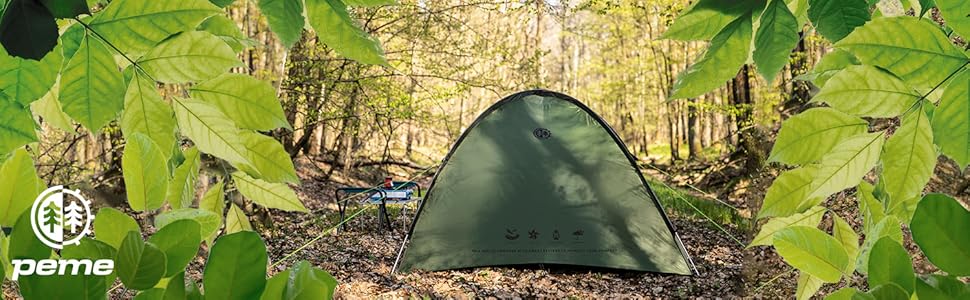 Tienda de campaña de color verde oscuro instalada en un entorno forestal, rodeada de frondosa vegetación y árboles