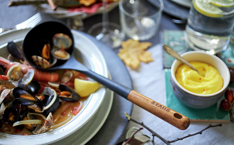 STAUB silicone soup ladle against a bowl of seafood.