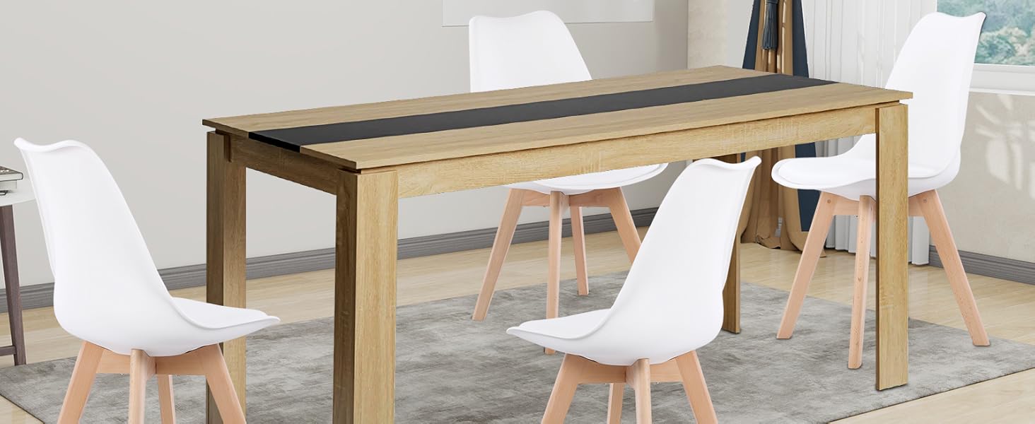 Esstisch aus Holz mit dunklem Mittelstreifen, gepaart mit vier weißen, geformten Plastikstühlen mit Holzbeinen. Es befindet sich in einem hellen Raum mit Vorhängen und Wandkunst.