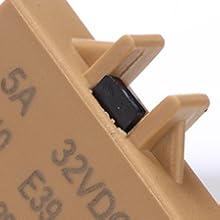 Close-up of a beige electronic component with visible text '5A' and '32VDC'. The part has a rectangular shape with protruding edges and a small black insert.