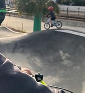 BMX cyclist performing aerial trick in skate park, captured mid-jump with bike silhouetted against sky. Multiple angles of the jump sequence shown.