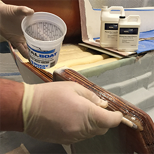 Using a brush to apply TotalBoat Penetrating Epoxy to a wooden transom