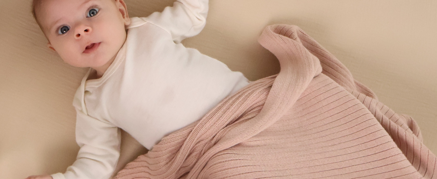baby with blush ribbed knitted blanket