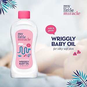 Text reads 'my little miracle WRIGGLY BABY OIL for silky soft skin'. White bottle with pink cap and details against blue tropical leaf accents.
