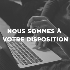 Tapez à la main sur le clavier d'un ordinateur portable. Le texte superposé en français se lit comme suit : « NOUS SOMMES À VOTRE DISPOSITION » (Nous sommes à