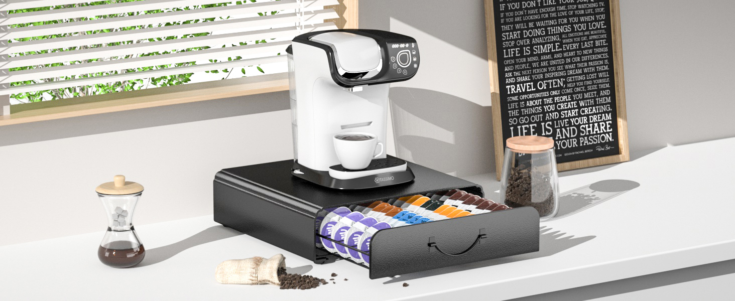 White coffee maker on black storage drawer unit with coffee accessories and menu board in background on white counter surface.