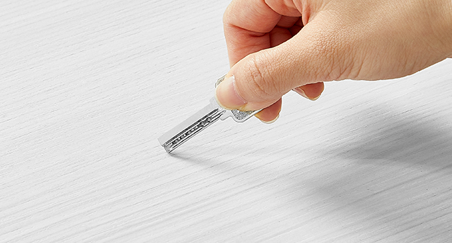 Nahaufnahme einer Hand, die einen kleinen, durchsichtigen Plastikstreifen mit Markierungen hält, möglicherweise zu Mess- oder Testzwecken