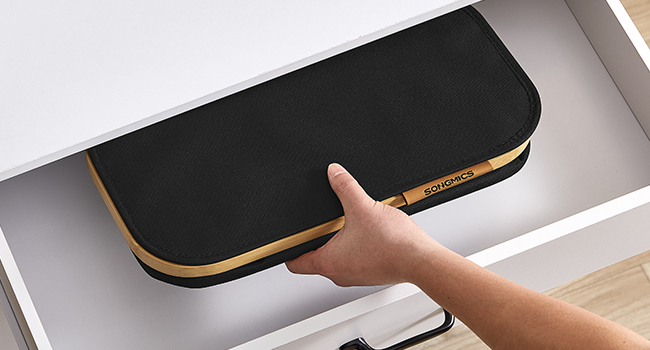 Fekete, téglalap alakú, arany szegéllyel ellátott eszköz, amelyet egy asztal alá szerelnek. A kéz a könnyű rögzítést mutatja, ami helytakarékos asztali kiegészítőre utal.