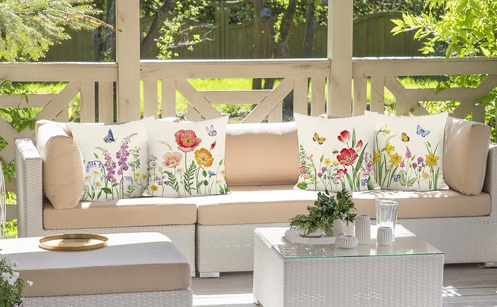 a white patio with a white sofa and a white coffee table with a floral pattern.