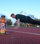 Protein drink in the foreground, athlete doing a pushup in the background