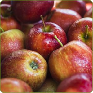 Primo piano di mele rosse fresche con buccia liscia e lucida. Alcune mele hanno steli e foglie visibili