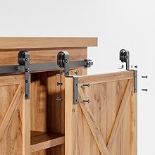 Beschlagsystem für Scheunentore aus Holz mit schwarzen Metallrollen und Schiene, montiert an einer weißen Wand.