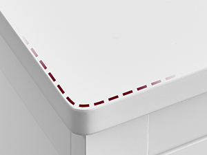 Közeli kép egy fehér felület széléről piros pontozott vonallal, amely esetleg vágó- vagy hajtogatóvezetőt jelez