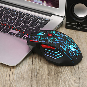 Gaming mouse with blue LED lighting and ergonomic design, featuring multiple buttons. Positioned next to a laptop keyboard and speaker on a wooden surface.