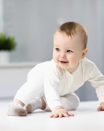 White cotton onesie or bodysuit shown on white surface in bright, clean setting with light grey background.