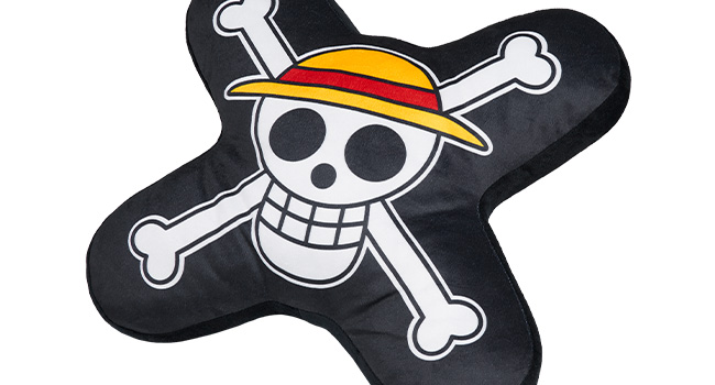 Black cushion or pillow shaped like a cartoon skull and crossbones. The skull wears a yellow straw hat with a red band.